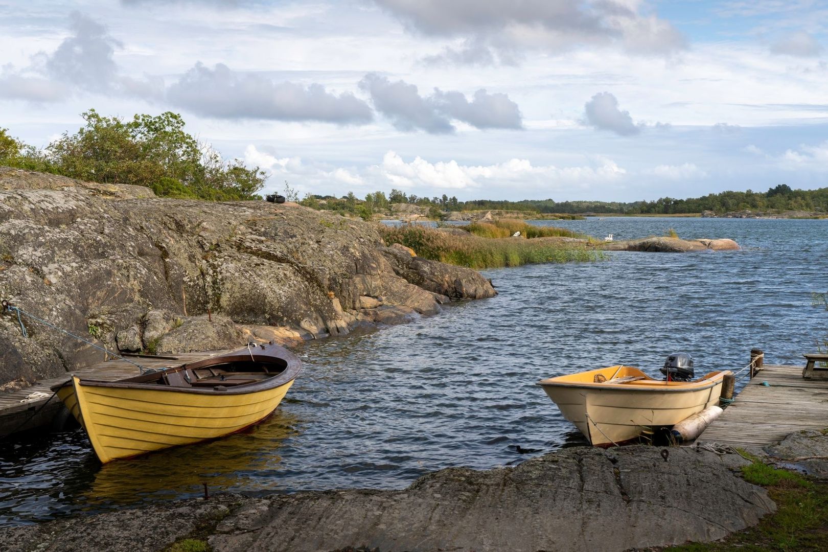 Två små träbåtar vid en klippig skärgårdsvik